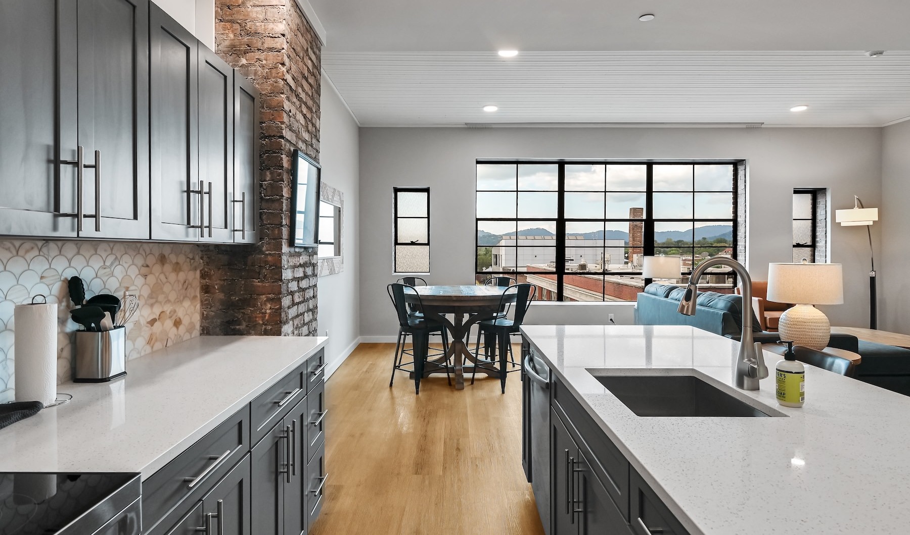 a kitchen with a large window and dark cabinets