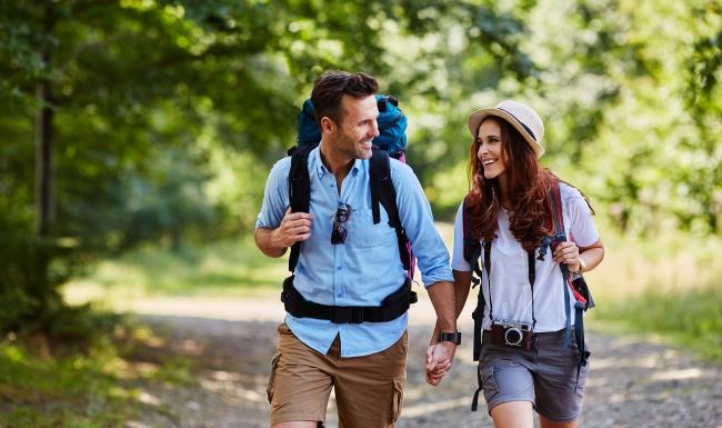 a man and woman walking on a path with backpacks